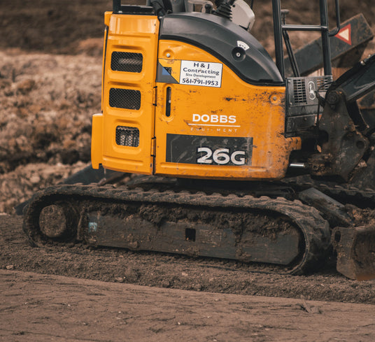 Mini excavator on aftermarket rubber tracks at a residential construction site — replacement rubber tracks for mini excavators, compact track loaders, and skid steers
