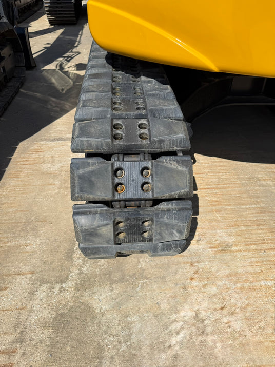Bolt-on rubber pads mounted on an excavator's steel track chain — aftermarket rubber and poly track pads that protect pavement, milling surfaces, and finished work